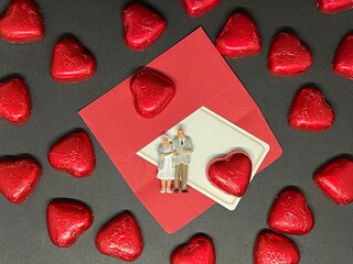 高齢者のカップルの人形とハート型のチョコレートと赤い封筒白いメッセージカード。