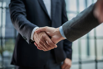 Two diverse professional business men executive leaders shaking hands at office meeting