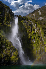 Obraz na płótnie Canvas Impressive waterfall at Milford Sound New Zealand. Mountains and coast in Fjordlands. Dramatic. 