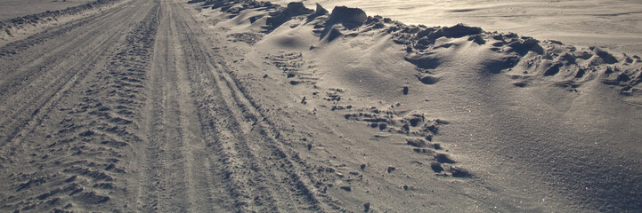 Winter road. Winter landscape of road. Snowy winter on the countryside, black and white picture. Highway leading through snowy fields. Drifts on the road.