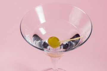 Martini glass with olive on a pink background. alcoholic drink