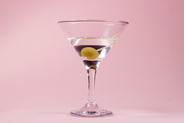 Martini glass with olive on a pink background. alcoholic drink