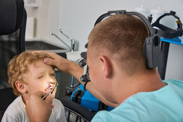 When examining a small child, the otolaryngologist uses modern equipment, a headlamp illuminator...