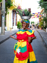 A woman in the classical Colombian dress with the fruit basket on her head on the streets of...
