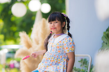 Cute smiling little girl eating an ice cream on a stick