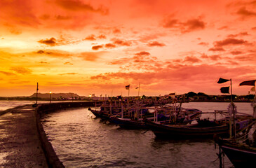sunset over the harbor, the evening sky and the silhouettes of several fishing boats on the pier 