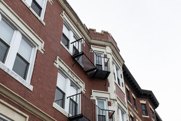 Elaborate architectural details on windows, overhangs, and top edge of a classic urban apartment building, metal balconies, horizontal aspect