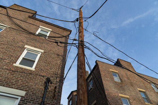 Upward view of the rear of two urban brick apartment buildings with a power pole and lines spanning between, horizontal aspect