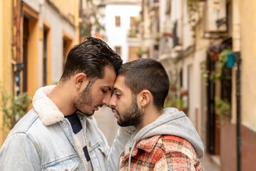 profile of young gay couple in love touching each other face to face outdoors