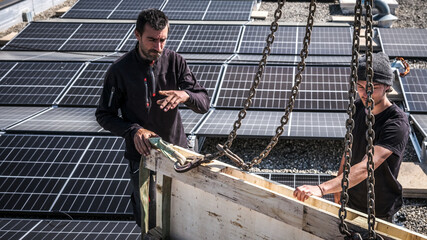 Male team engineers installing stand-alone solar photovoltaic panel system. Electricians mounting...