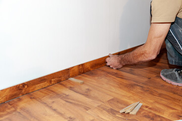 Worker, Carpenter installing laminate flooring. Installing molding trim Vinyl Plank Flooring.