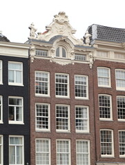 Fototapeta na wymiar Amsterdam Canal House Facade with Sculpted Roof Decoration, Netherlands