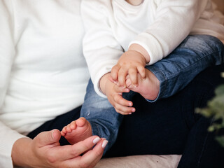 The feet and hands of a baby in the hands of his/her mother. Parenting, family life and mother love.