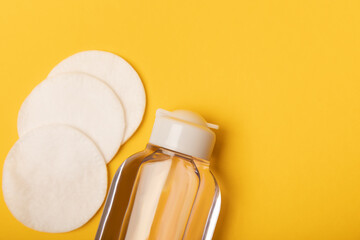 Micellar water and cotton pads on a bright yellow background. Makeup and sebum removal toner....