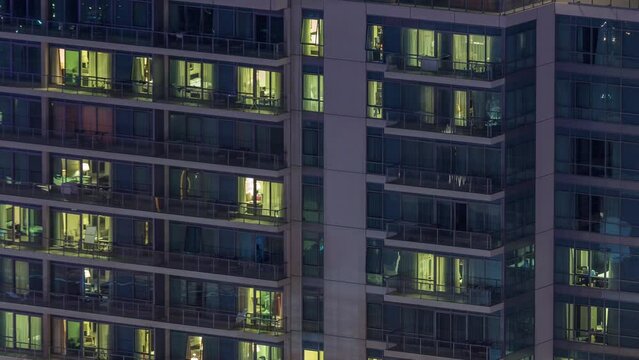 Windows lights in residential high-rise buildings timelapse at night. Multi-level skyscrapers with illuminated rooms inside