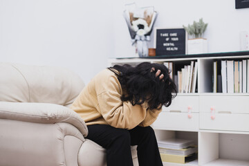 A woman sitting alone on sofa and depressed, mental health awareness concept.