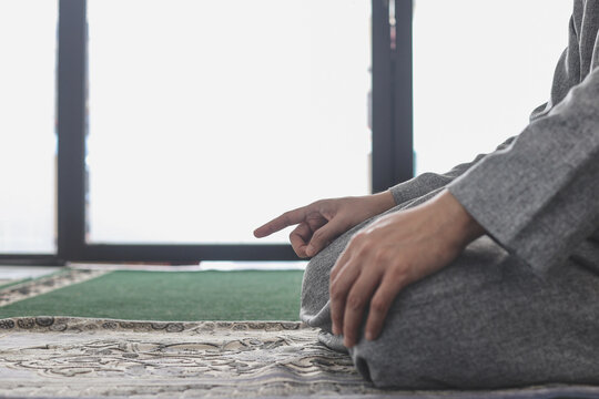 Close-up of Muslim man praying salat with fingers movement at the mosque.