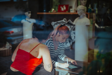 Tattoo artist drawing while her client is watching