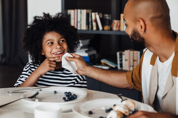 Happy father with son sitting by table while having breakfast at home