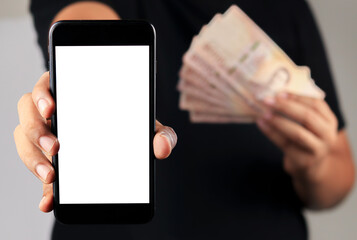 Asian man stand and holding smart phone screen another hand showing Thai baht money over grey background.