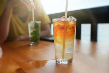 Glass of Mai Tai cocktail in front of woman in bar.