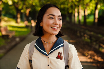 Young beautiful smiling asian woman walking outdoors in park