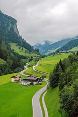 Winding asphalt road through the Grossarl valley, passing alpine farms and green pastures, Grossarl, Austria.