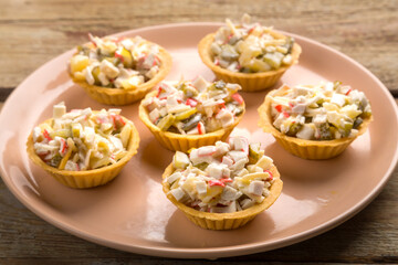 Shrimp salad in tartlets on a plate on a wooden table.
