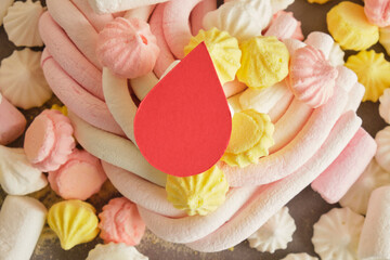 blood drop and meringue and marshmallows on red background, diabetes concept