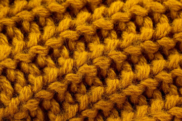Bright ocher color knitted textured handmade fabric as a textile background close up.