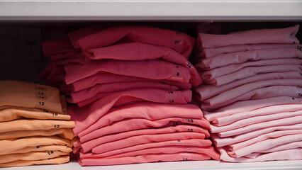 Stack of cloth different colors and sizes on the shelves in a clothes store