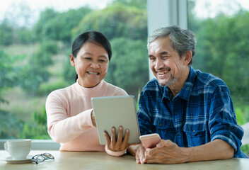 asian senior couple enjoy chatting internet online connection, older adults people sitting and laughing together when looking at tablet computer