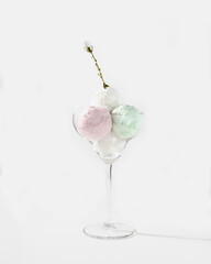 Vanilla, mint and strawberry ice cream scoops in a glass bowl with decorative dessert spoons.