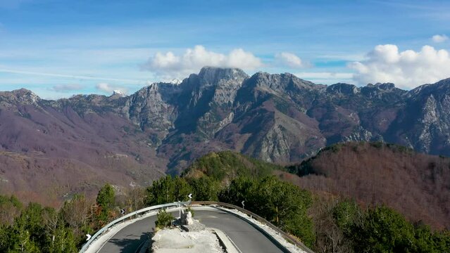 Aerial 4K drone footage of Theth National Park Albania, beautiful albanian alps mountains and road to small town with rocky hills view and curves with white clouds on blue sky