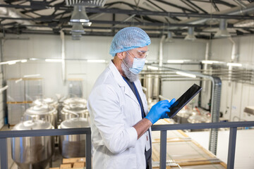 Brewer using a digital device at a beer plant (