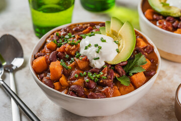 Chili sweet potatoes and black beans with tomatoes, celery close-up in a pan on the table. Horizontal top view from above