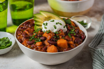 Chili sweet potatoes and black beans with tomatoes, celery close-up in a pan on the table....