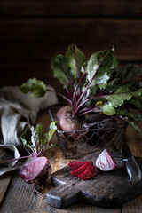 Fresh organic red beets with leaves in a wicker basket on a wooden table. Natural organic vegetables. Autumn harvest. Rustic