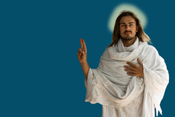 Jesus-type handsome man in white robes against a dark blue background with finger symbol