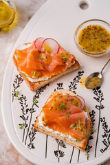 Two open sandwich, toast with smoked salmon, cream cheese, watercress, on white concrete table. Morning healthy breakfast with fish. side view, close up. clean eating.
