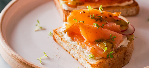 Two open sandwich, toast with smoked salmon, cream cheese, watercress, on white concrete table. Morning healthy breakfast with fish. side view, close up. clean eating.