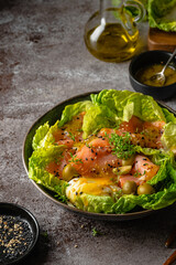 Salmon salad - smoked salmon hard boiled eggs, olives, watercress, sesam and green vegetables on dark brown table. Healthy food. Clean Eating. Paleo diet.