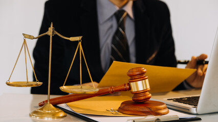 Business and lawyers discussing contract papers with brass scale on desk in office. Law, legal services, advice, justice and law concept.