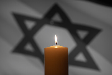 Burning candle on Israel flag background. International Holocaust Remembrance Day, January 27.