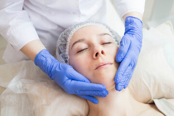 Fototapeta premium The cosmetologist making massage the patient in the spa salon. Facial care.