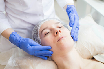 Fototapeta premium The cosmetologist making massage the patient in the spa salon. Facial care.