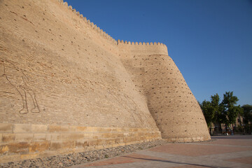 Fototapeta na wymiar High solid brick walls of the Ark fortress in Bukhara in Uzbekistan. Tourism concept.