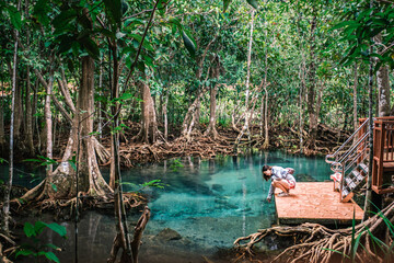 Girl traveler enjoying beautiful water of Tha Pom Klong Song Nam, Abundant mangrove forest where sea water meet with fresh water, Krabi Thailand December 2022