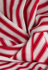 Fototapeta premium Vertical image of red and white striped fabric is displayed in swirls and folds with a center emphasis in the pattern of the material.