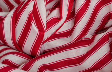 Red and white striped fabric closeup shows folds and swirls of material in a horizontal display. It looks like a bright candy stripe fabric.
